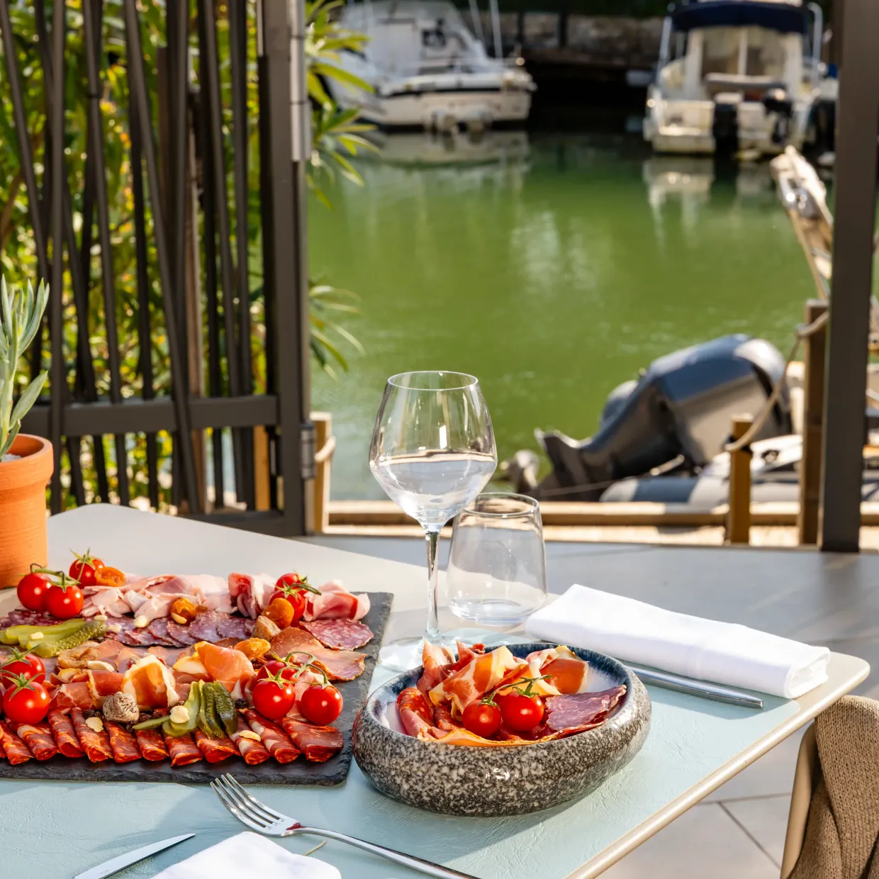 Table with charcuterie plate, wine glass, and view of a canal with boats