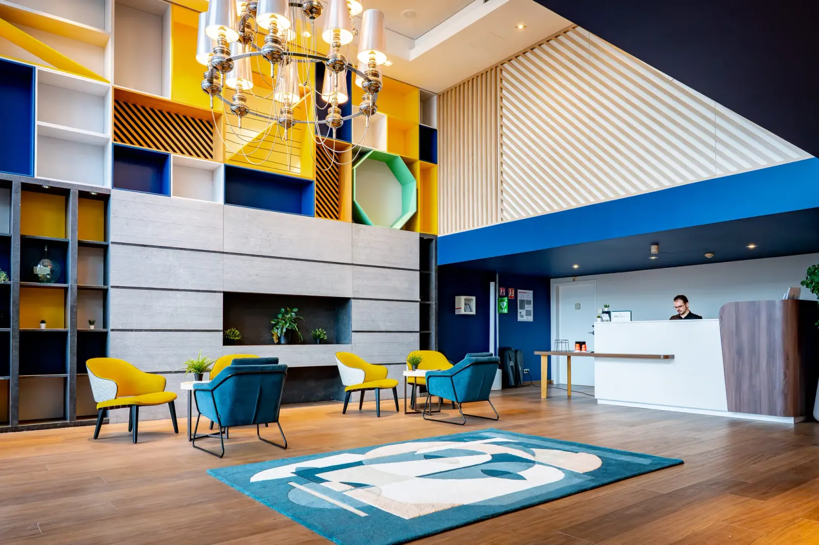 A modern reception hall with colorful chairs, a reception desk, and suspended lighting.