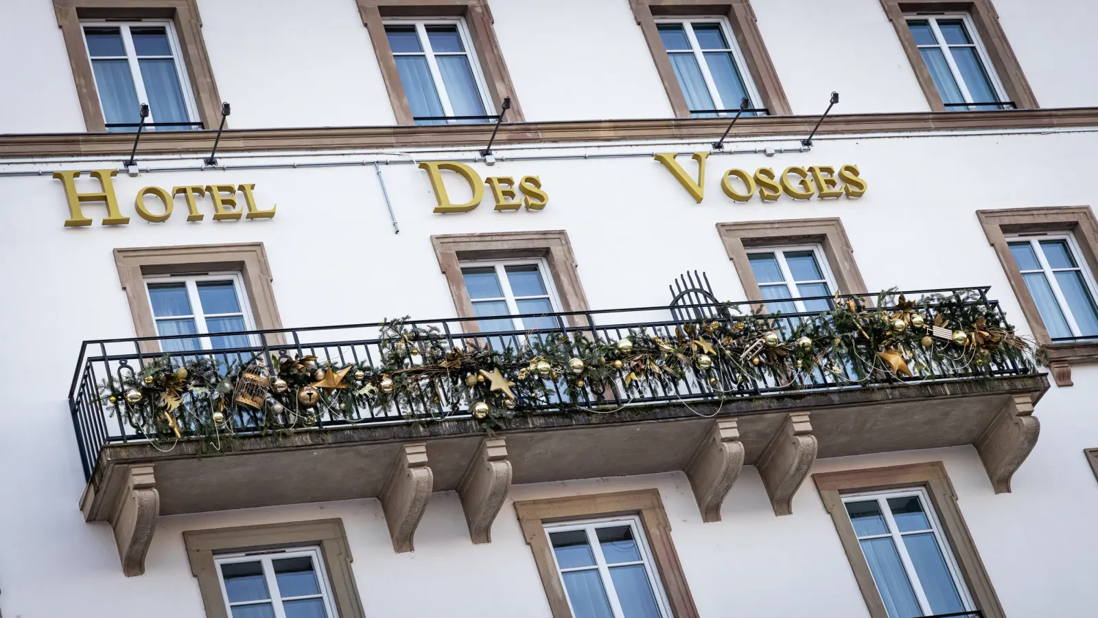 Facade of a hotel with a balustrade decorated with garlands and golden stars