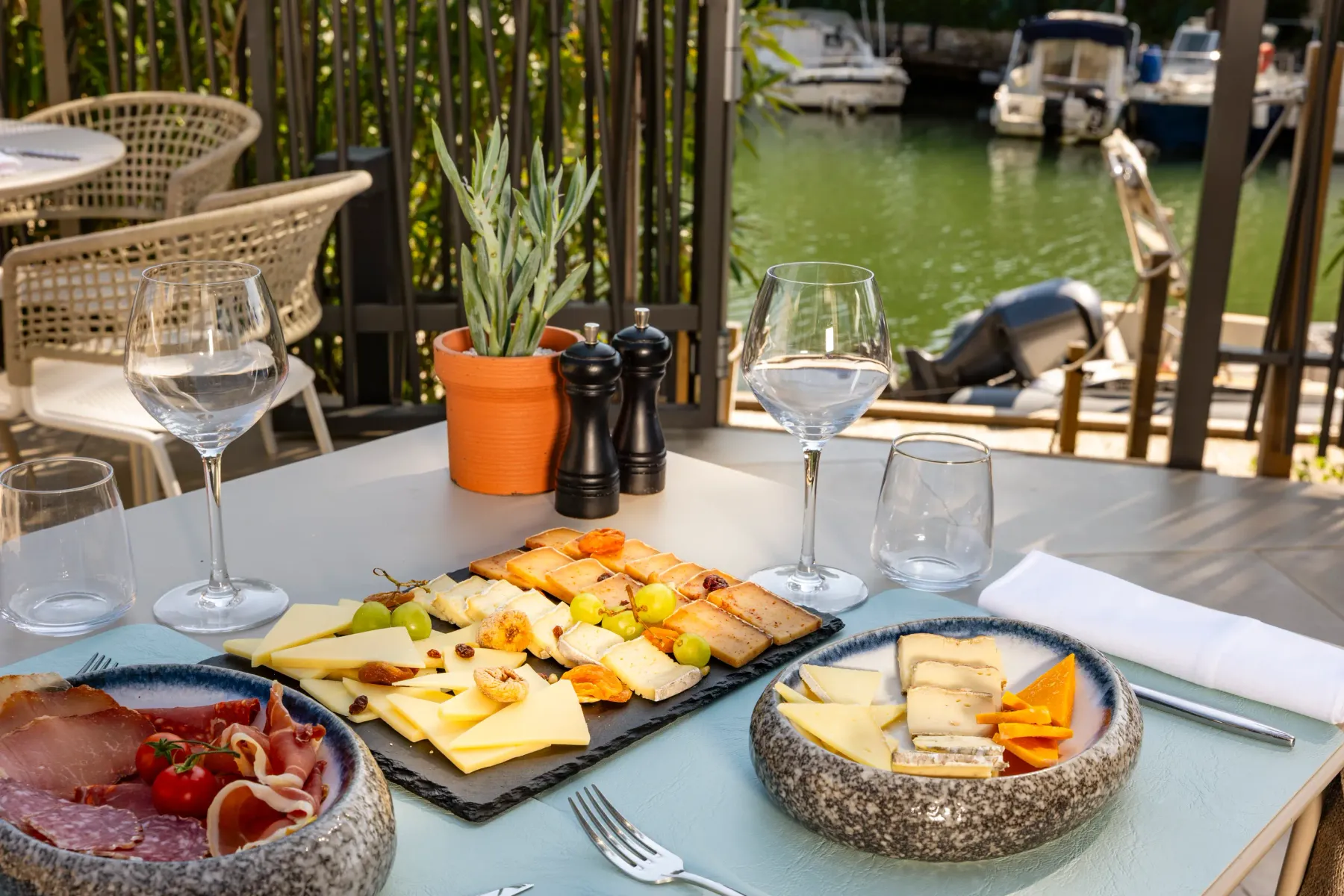 Table with charcuterie platter, cheeses, glasses, and view of a canal with boats