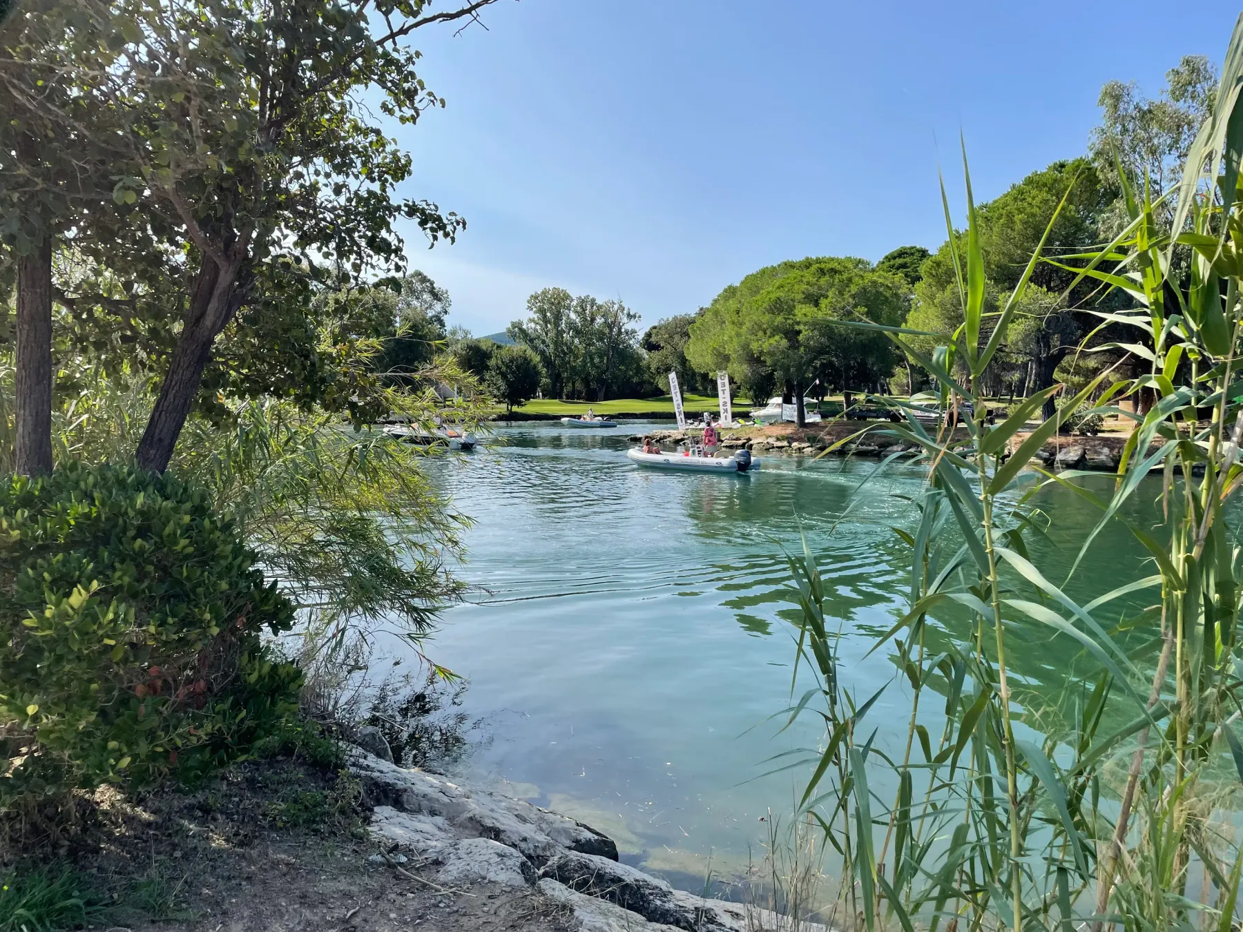 A body of water surrounded by vegetation with people swimming and relaxing on rafts.