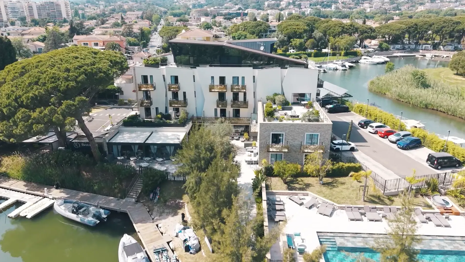 Aerial view of a riverside hotel complex with pool, restaurant, and dock