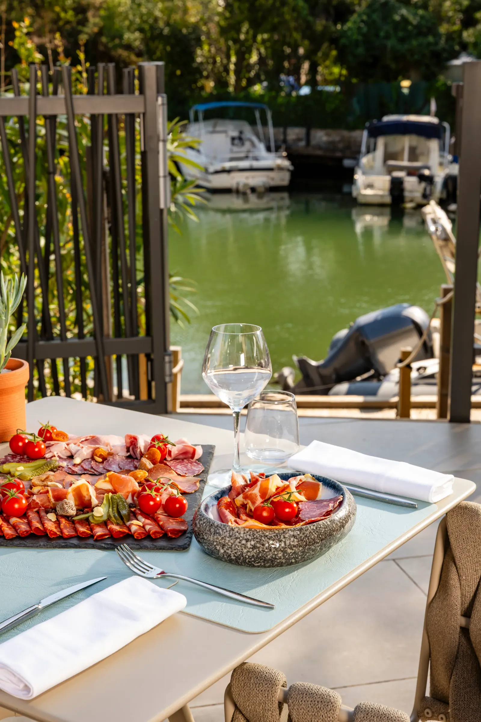 Table with charcuterie plate, wine glass, and view of a canal with boats