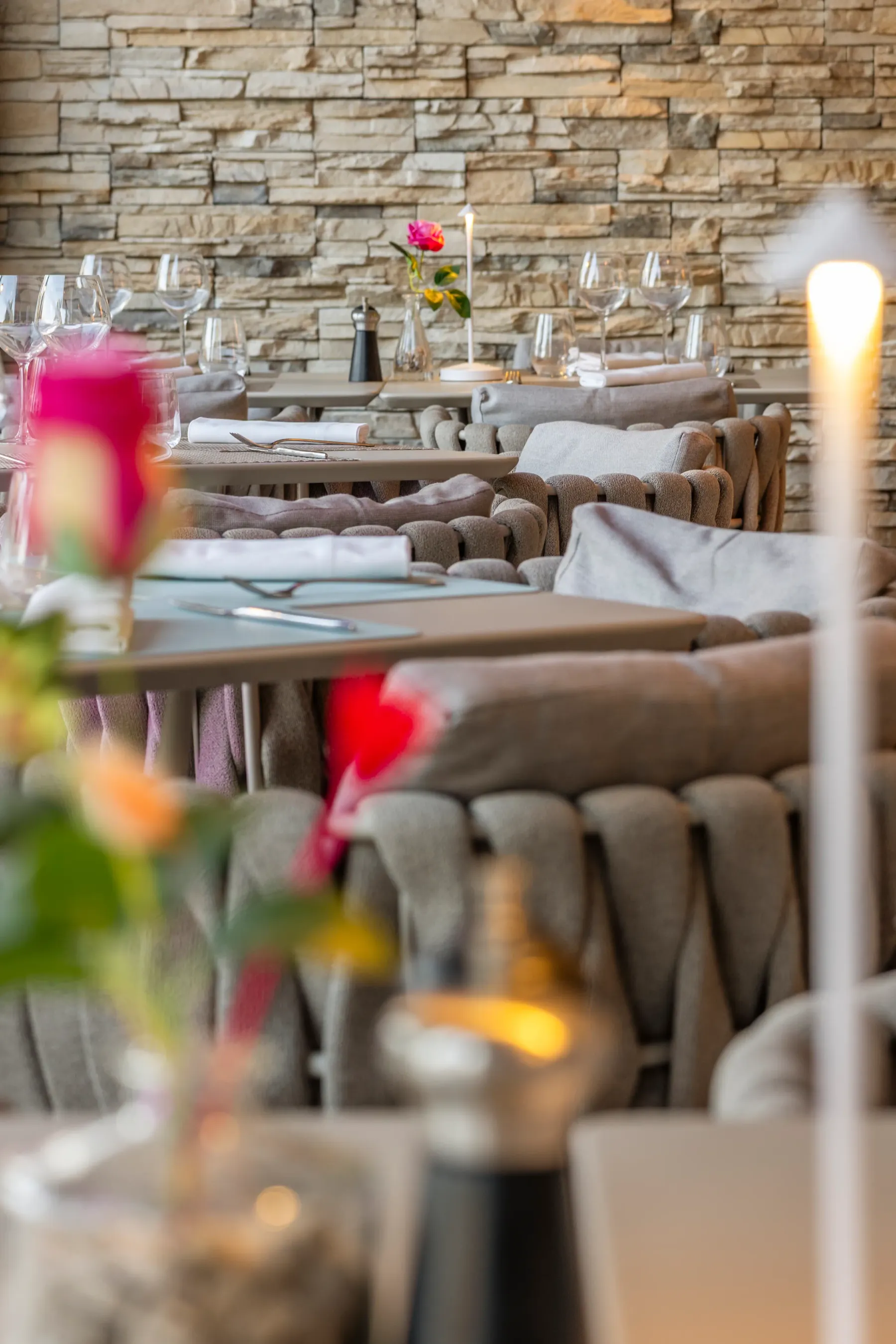 Tables dressées avec verres, couverts et serviettes dans un cadre rustique avec des bougies et des fleurs
