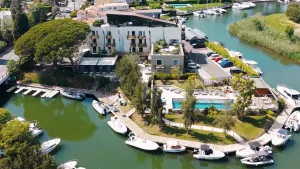 Vue aérienne d'un complexe hôtelier avec piscine et marina, entouré d'eau et de bateaux amarrés