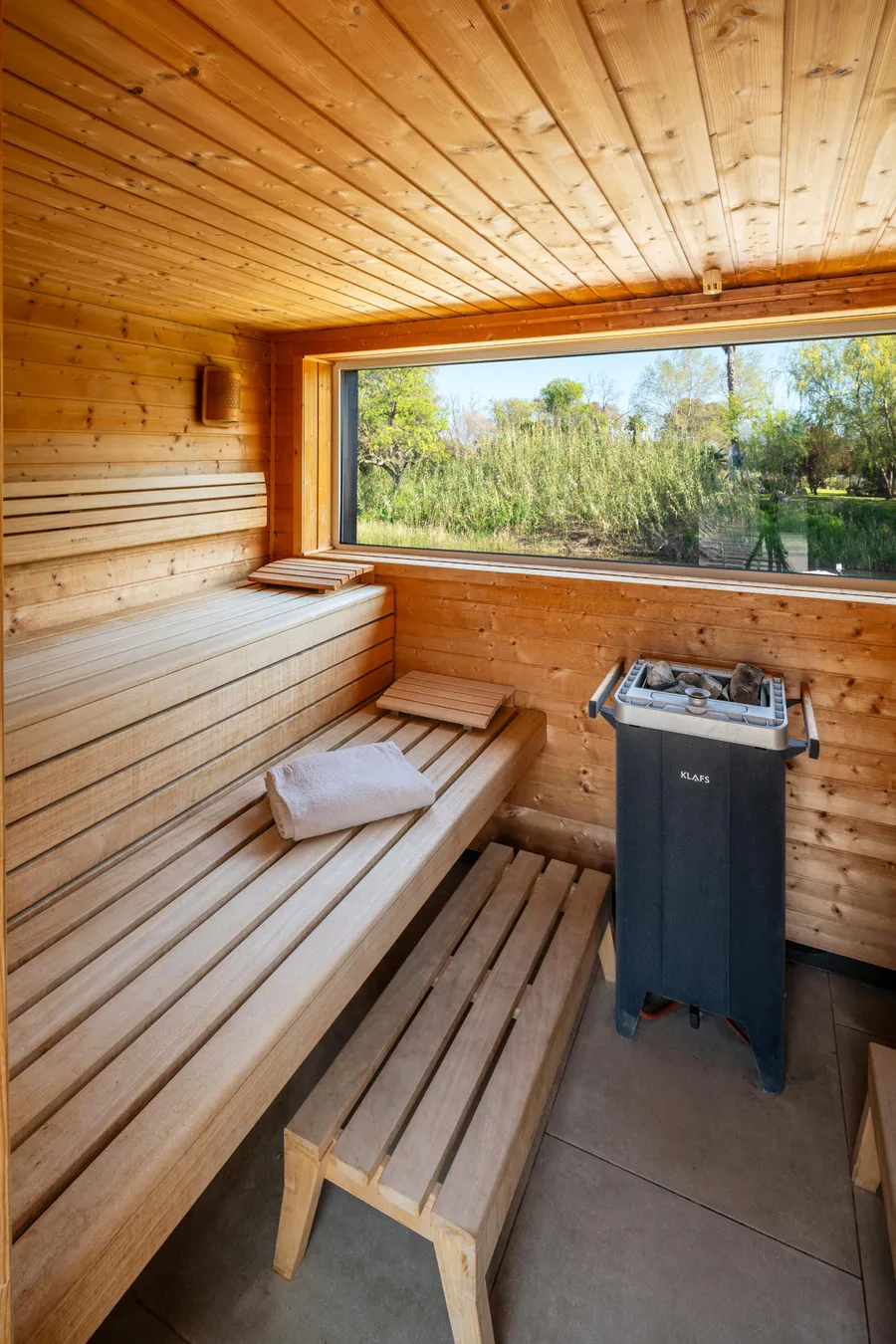 Wooden sauna with benches, electric heating, and an outdoor view through a window